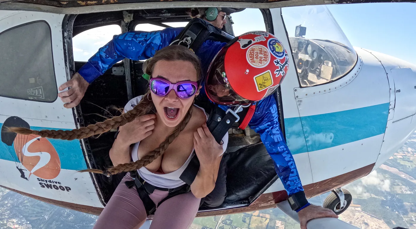 A tandem skydiver beginning freefall beside the aircraft